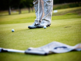 two golf balls on golf course green with flag in foreground