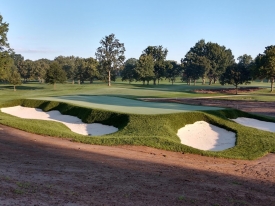 Golf course with sand bunkers and trees in the background at sunset