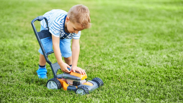 Young child playing with lawn mower tow in a perennial ryegrass lawn