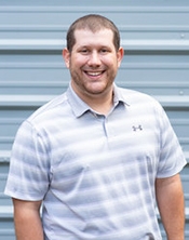 Corporate portrait of a man in a grey and white striped polo shirt 