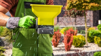 Person spreading fertilizer onto grass