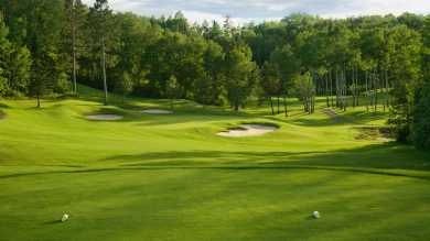 Golf course tee box with green fairways under blue skies.