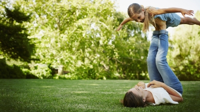 Mother and daughter in backyard in the shade with large bush in the background