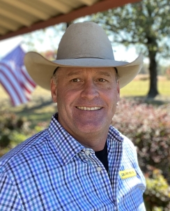 Portrait of a man in a tan cowboy hat and striped dress shirt 