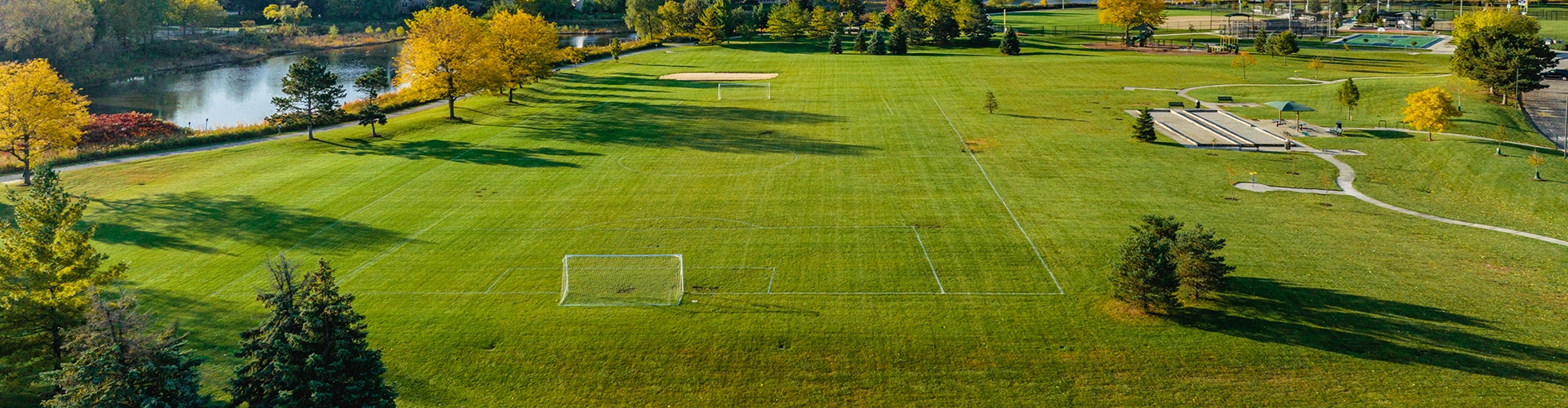 Aerial view of soccer field with a river and trees in background