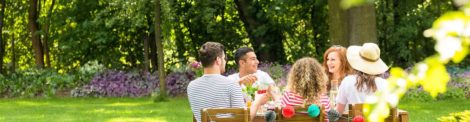 Friends seated around a table outside in beautiful green grass