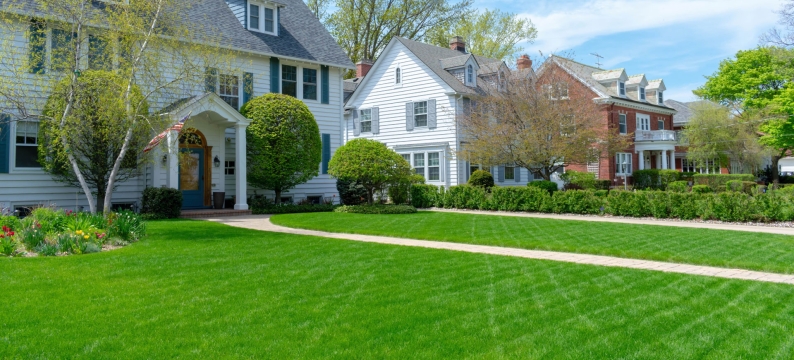 White, two story houses with green, lush lawn.