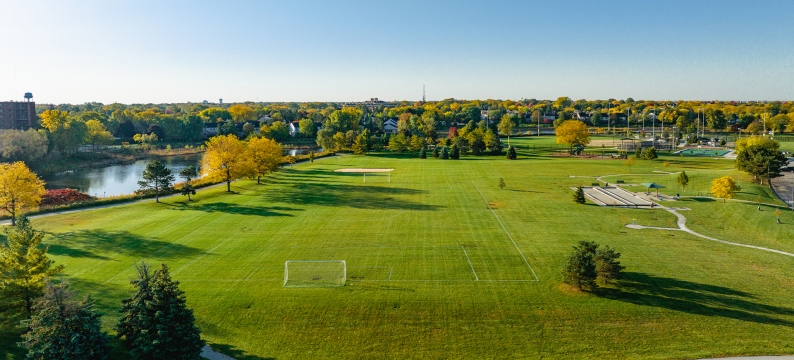 Aerial view of soccer field with a river and trees in background