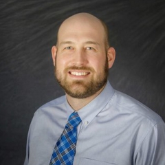 Corporate headshot of a man on a black background
